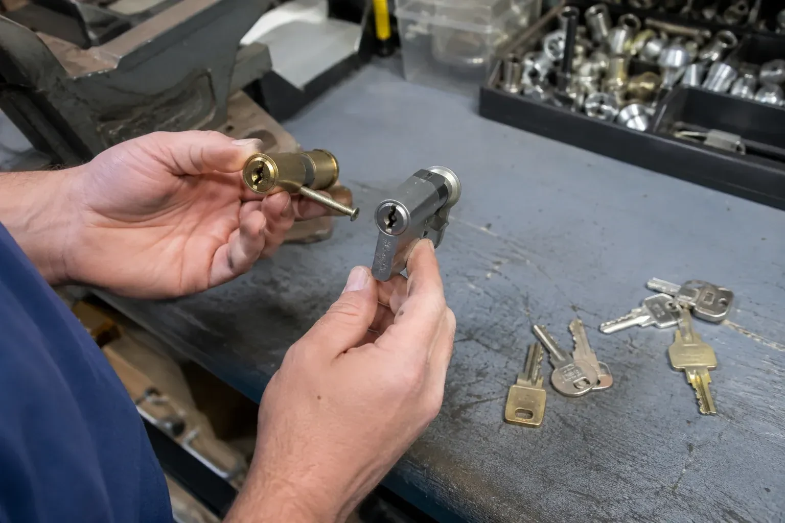 Hands comparing detached lock cylinders beside loose keys on a workbench. — Broken Key Extraction, London