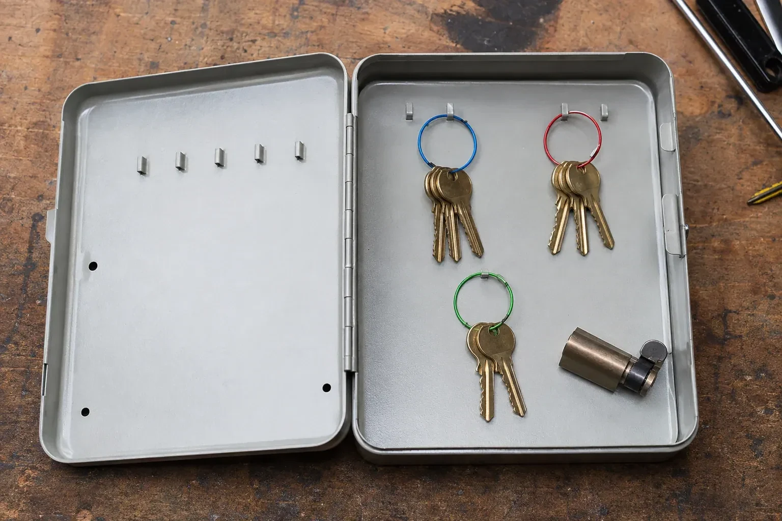 Three groups of keys on colored rings in an open metal key cabinet. — Master Key System Design, London